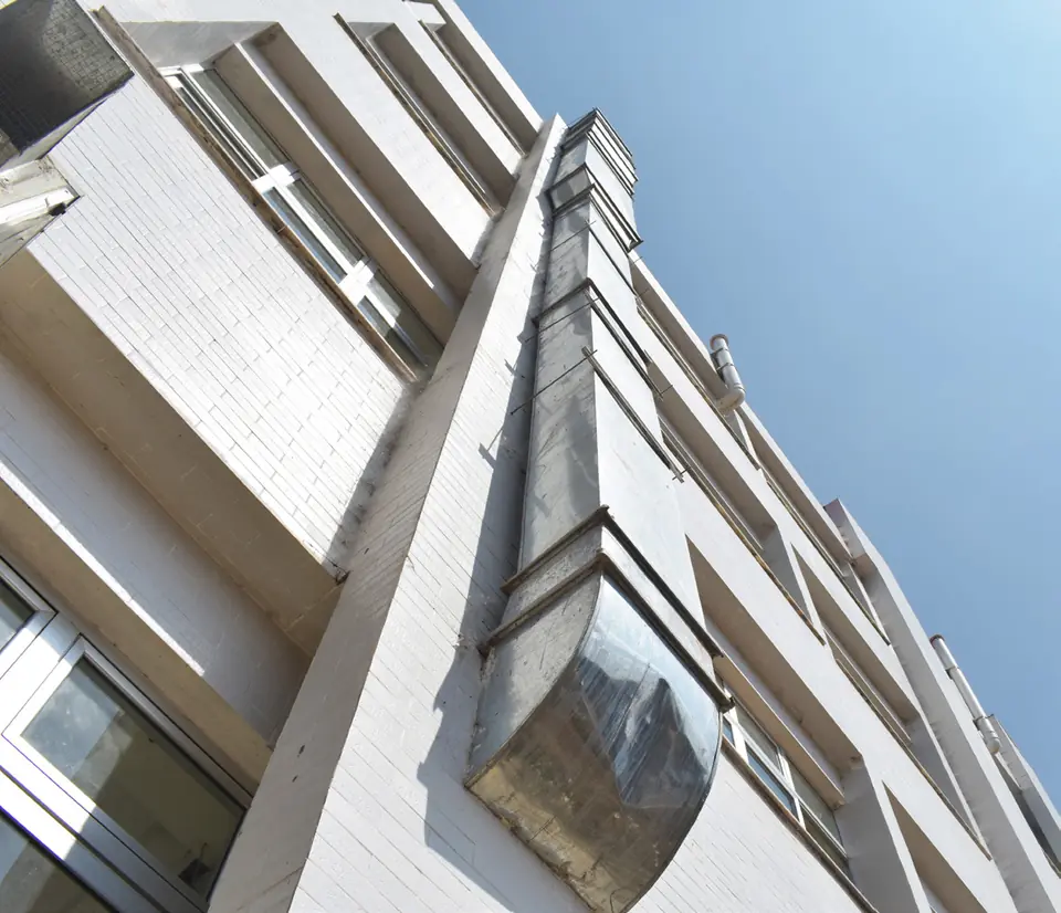Galvanized vertical duct riser on the building exterior, seen from below